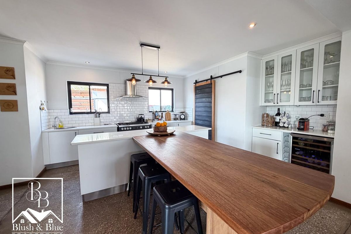 Modern kitchen featuring white cabinetry, subway tile backsplash, integrated wine fridge, gas cooktop, and a large wooden breakfast bar island.