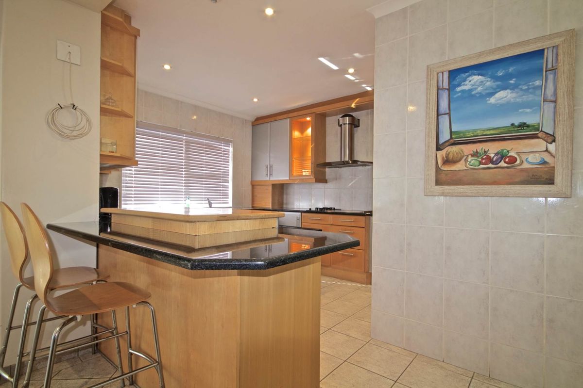 A functional kitchen featuring wood-finish cabinetry, granite countertops, a breakfast bar, and tiled flooring, offering a practical layout for daily meal preparation.