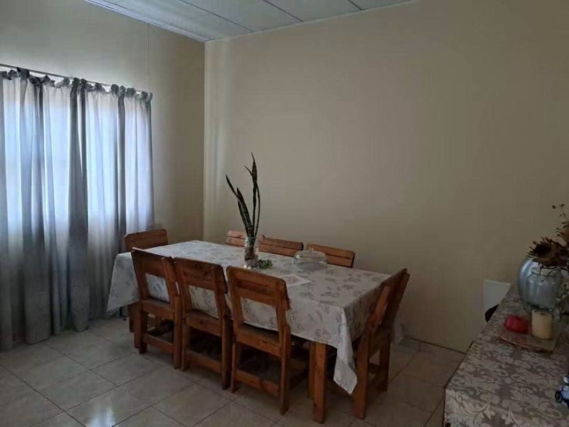 A functional dining room featuring tiled flooring and a drop ceiling, providing a neutral space for family meals.