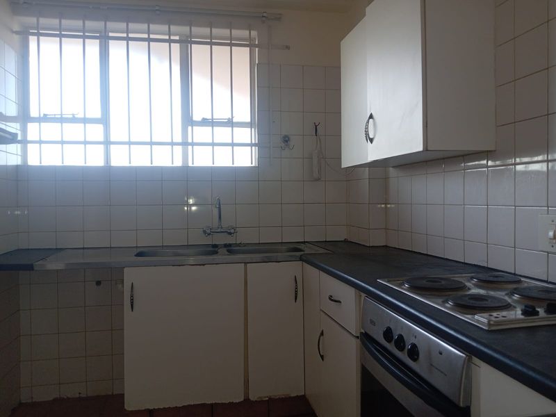 A functional kitchen featuring built-in cabinetry, a double sink, and an integrated electric hob and oven with tiled splashbacks.