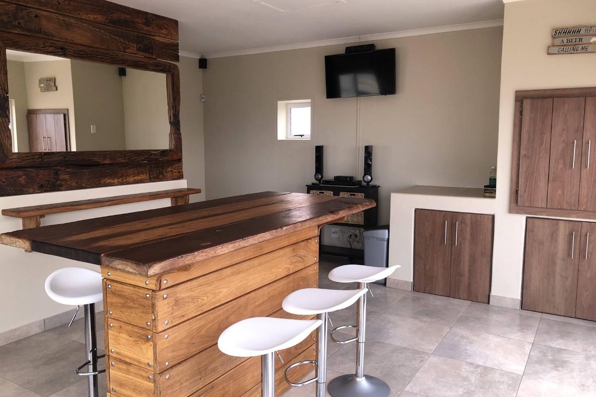 A dedicated home bar area featuring a custom wooden bar counter, built-in storage cabinetry, and neutral tiled flooring.
