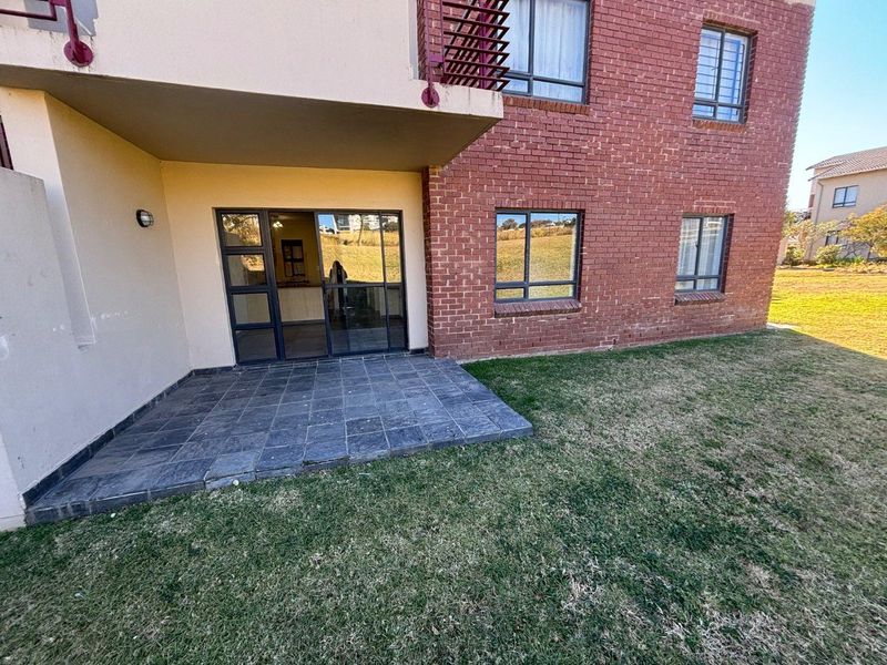 Rear view of the apartment featuring a paved patio area, brick exterior walls, and direct access through a sliding glass door.