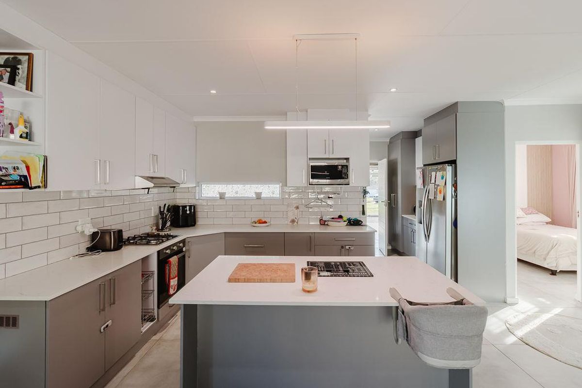 Modern kitchen featuring a central island with quartz countertops, subway tile backsplash, built-in appliances, and sleek cabinetry with ample storage space.