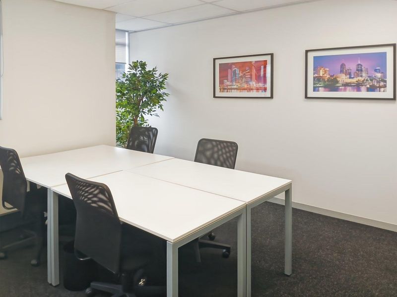A clean, professional office space featuring neutral walls, carpeted flooring, and a suspended ceiling, suitable for a productive work environment.