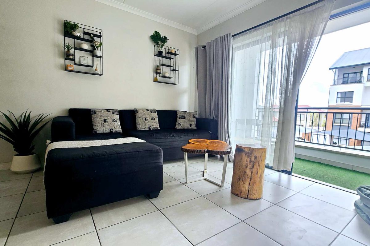 A bright living room featuring tiled flooring and a large sliding glass door that provides direct access to an outdoor balcony area.