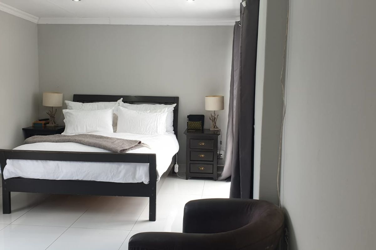 A well-lit bedroom featuring tiled flooring, neutral wall finishes, and recessed ceiling lighting.