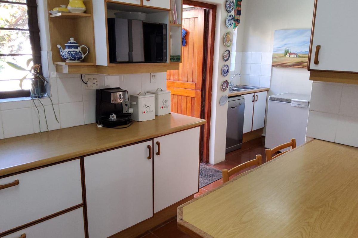 A functional kitchen featuring white cabinetry, laminate countertops, tiled backsplash, and direct access to an exterior timber door.