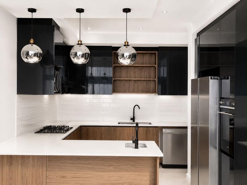 Modern kitchen featuring high-gloss black cabinetry, wood-grain accents, white quartz countertops, subway tile backsplash, and integrated appliances with contemporary pendant lighting.