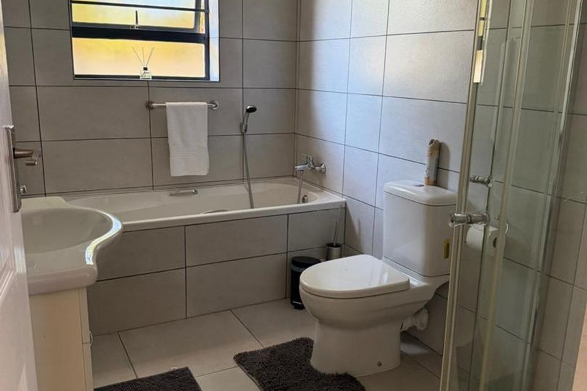 A modern bathroom featuring floor-to-ceiling tiling, a built-in bathtub, a separate glass-enclosed shower, and a pedestal basin.
