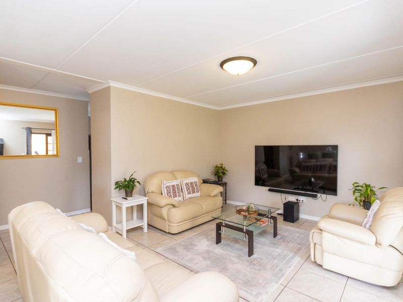 A comfortable living room featuring neutral wall tones, tiled flooring, and a coved ceiling, providing a functional and well-lit space for relaxation.