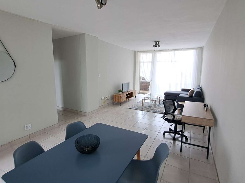 An open-plan living and dining area featuring neutral tiled flooring and large sliding glass doors that provide ample natural light.