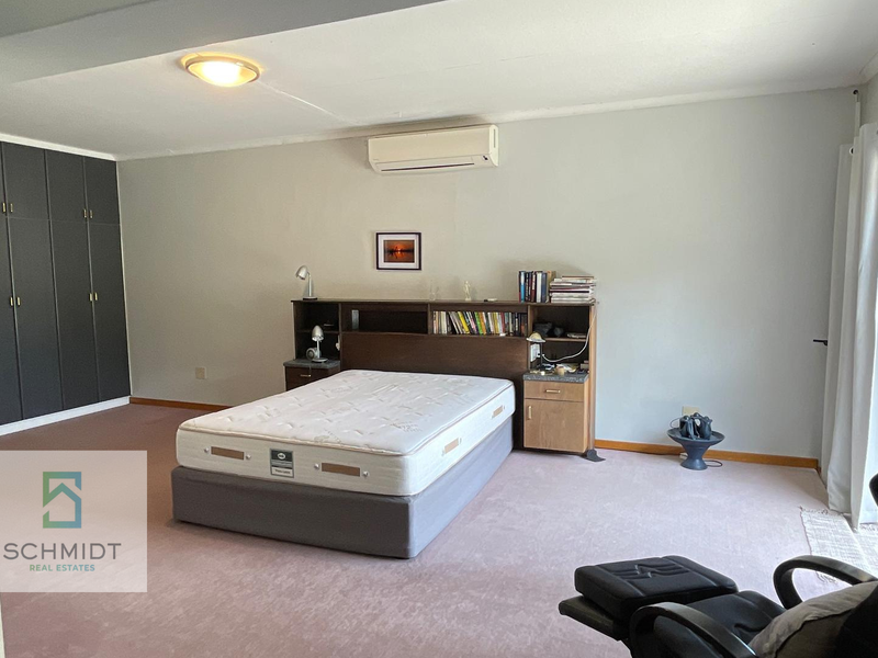 Spacious bedroom featuring built-in cupboards, a split-system air conditioner, and direct access to the outdoors via a sliding glass door.