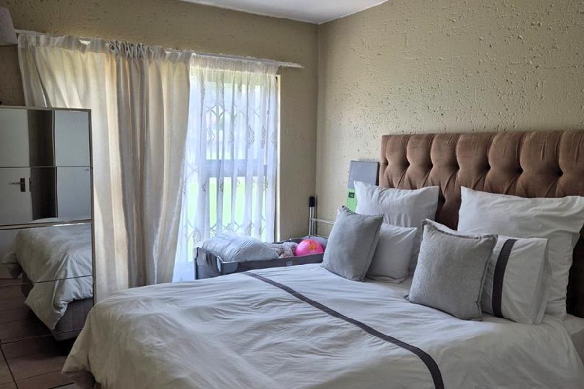 A bedroom featuring tiled flooring, textured wall finishes, and a ceiling-mounted light fixture, with access to natural light through a sliding door.