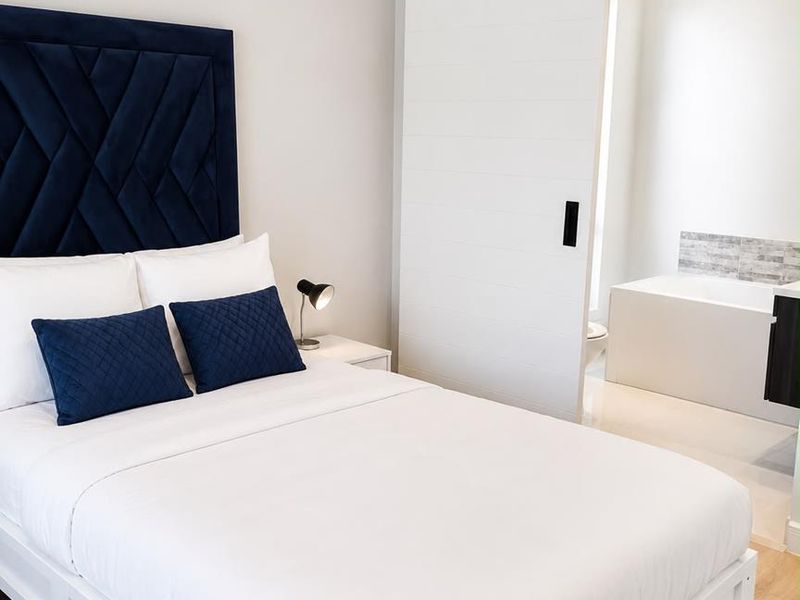 Modern bedroom featuring light laminate flooring and a sliding barn door providing direct access to an en-suite bathroom.
