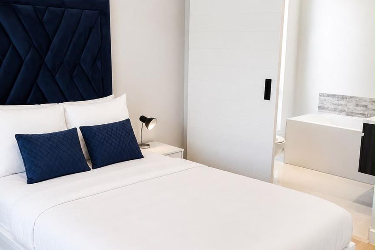 Modern bedroom featuring light laminate flooring and a sliding barn door providing direct access to an en-suite bathroom.