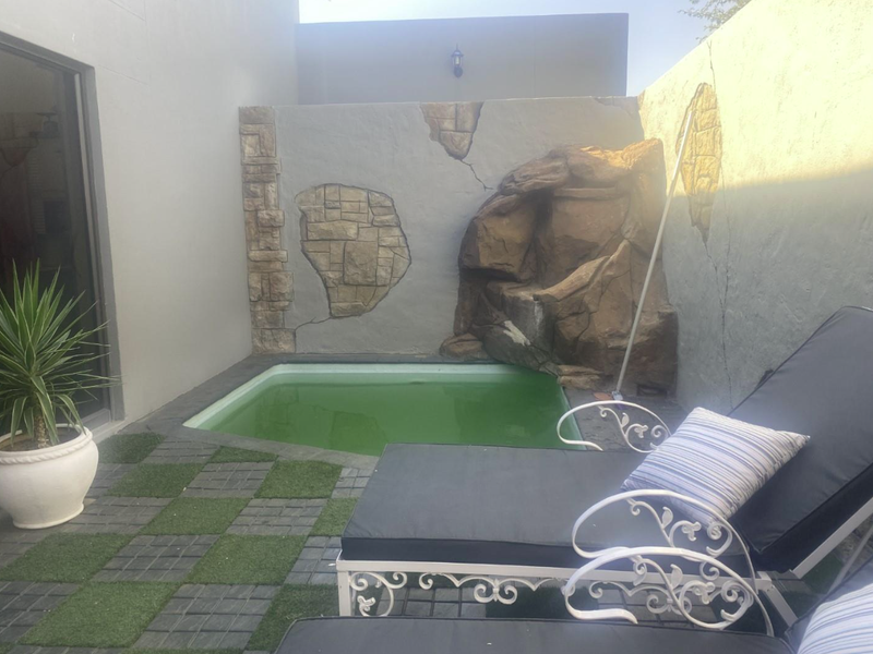 Small courtyard area featuring a plunge pool with a decorative rock water feature, paved surround, and artificial grass accents.