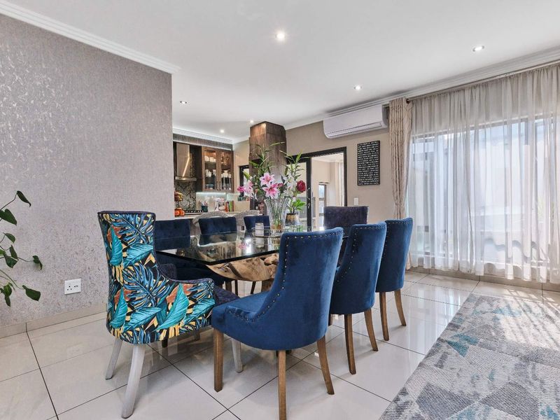 An open-plan dining area featuring polished porcelain tiles, a textured feature wall, and a split-system air conditioner, seamlessly connecting to the kitchen.