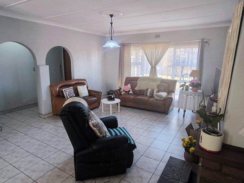 A spacious living room featuring tiled flooring, a brick fireplace, and distinctive archways leading to adjacent areas, offering a comfortable and functional living space.