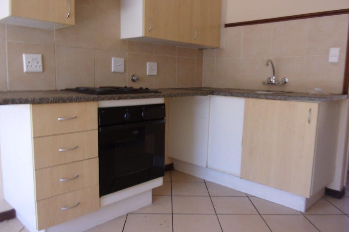 A functional kitchen featuring light wood-finish cabinetry, granite countertops, a built-in oven, gas hob, and tiled flooring.