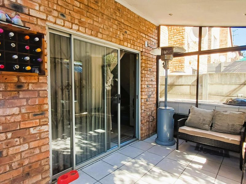 A covered patio area featuring exposed brick walls, tiled flooring, and large sliding glass doors providing access to the interior living space.