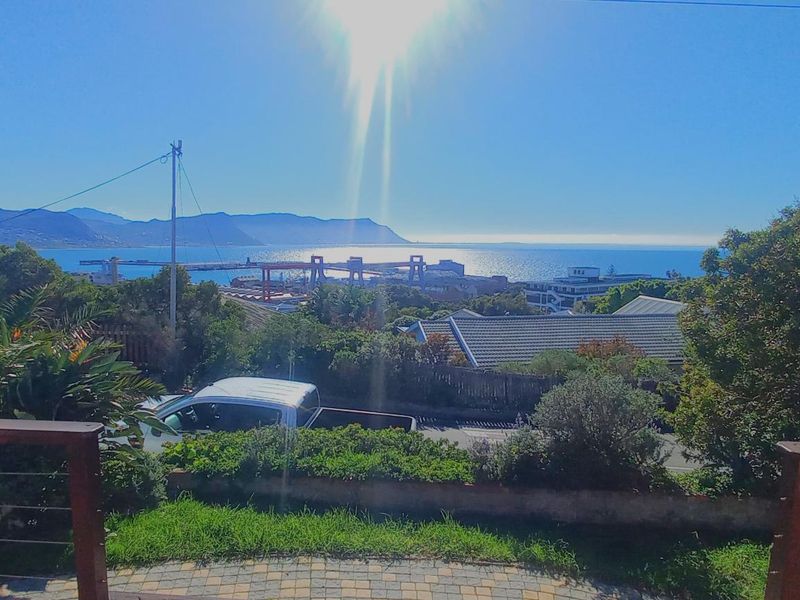 A scenic elevated view overlooking the coastal landscape, harbour, and distant mountains, captured from a residential property.