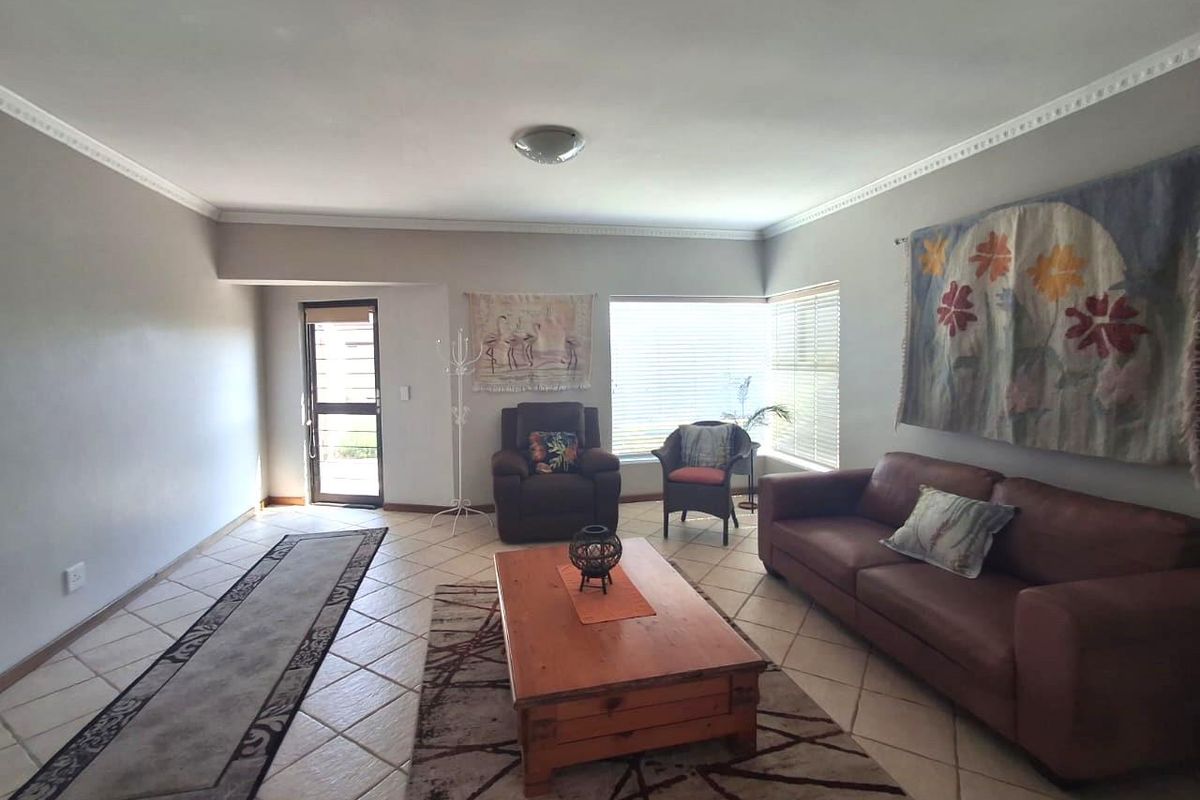 Spacious living room featuring neutral walls, tiled flooring, and crown molding, providing a comfortable and well-lit area for relaxation.