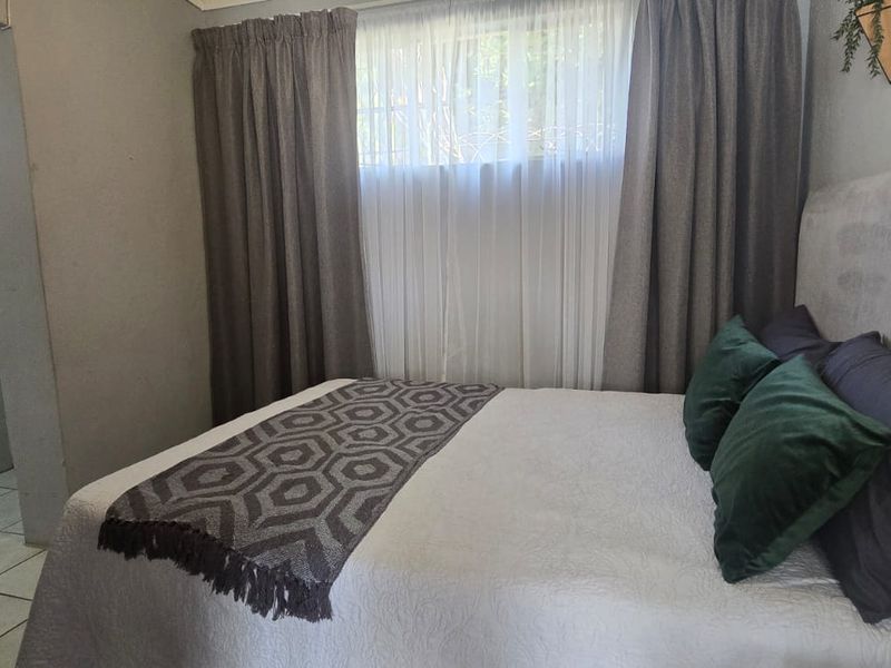 A bedroom featuring an adjoining en-suite bathroom with a vanity and tiled finishes, offering a functional layout.