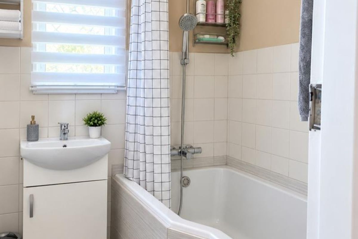 A clean and functional bathroom featuring a vanity basin, a bathtub with a shower mixer, and tiled wall finishes.