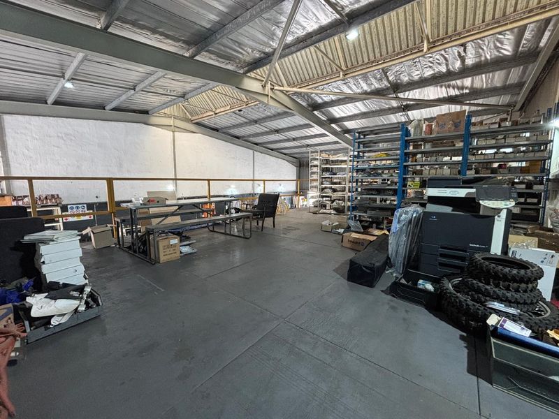 Industrial mezzanine utility space featuring exposed steel roof structure, metal roofing, and integrated industrial shelving units suitable for storage or workspace.