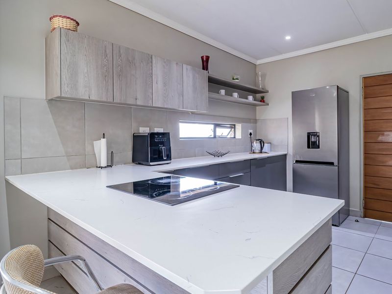Modern kitchen featuring sleek quartz countertops, built-in cabinetry, an integrated induction hob, and stylish tiled finishes in a clean, contemporary layout.