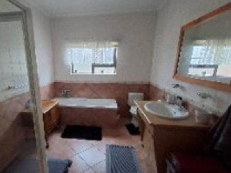 A functional bathroom featuring a built-in vanity, bathtub, toilet, and shower enclosure with tiled finishes throughout.