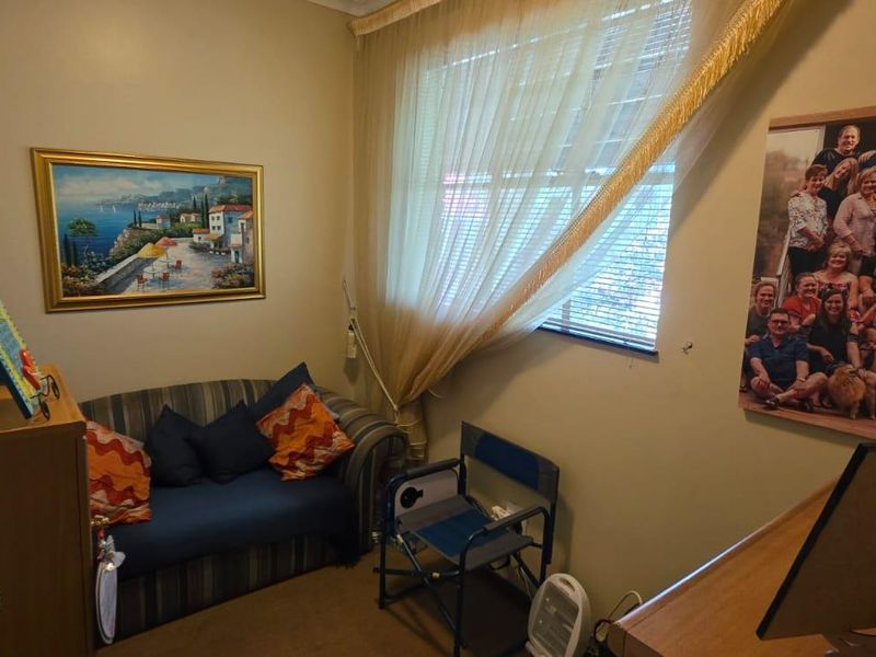 A compact bedroom featuring a window with security bars and neutral wall finishes.