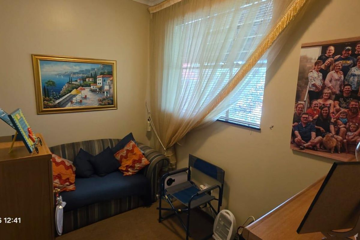 A compact bedroom featuring a window with security bars and neutral wall finishes.