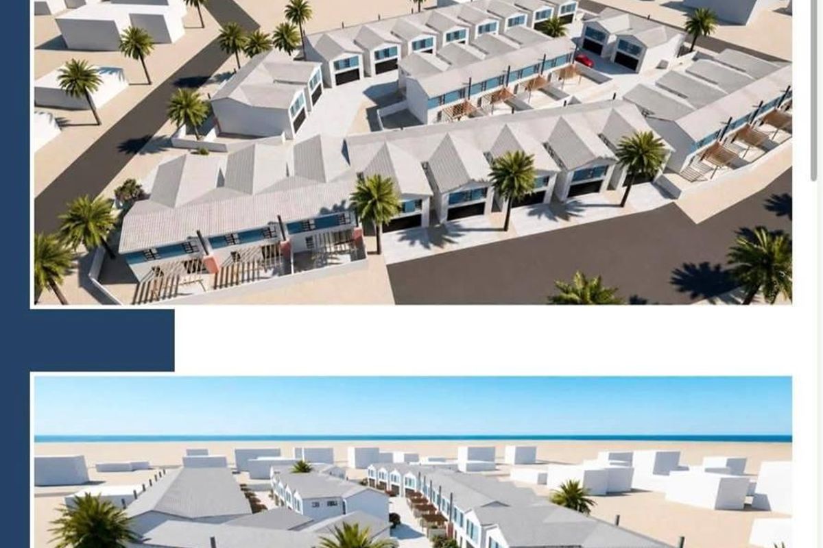 An aerial perspective of a townhouse development featuring multiple units, paved driveways, and landscaped outdoor areas within a secure complex.
