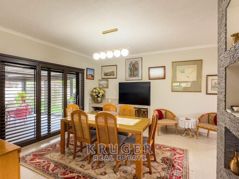 Spacious dining room featuring tiled flooring, modern lighting, and large sliding glass doors providing seamless access to the outdoor patio area.