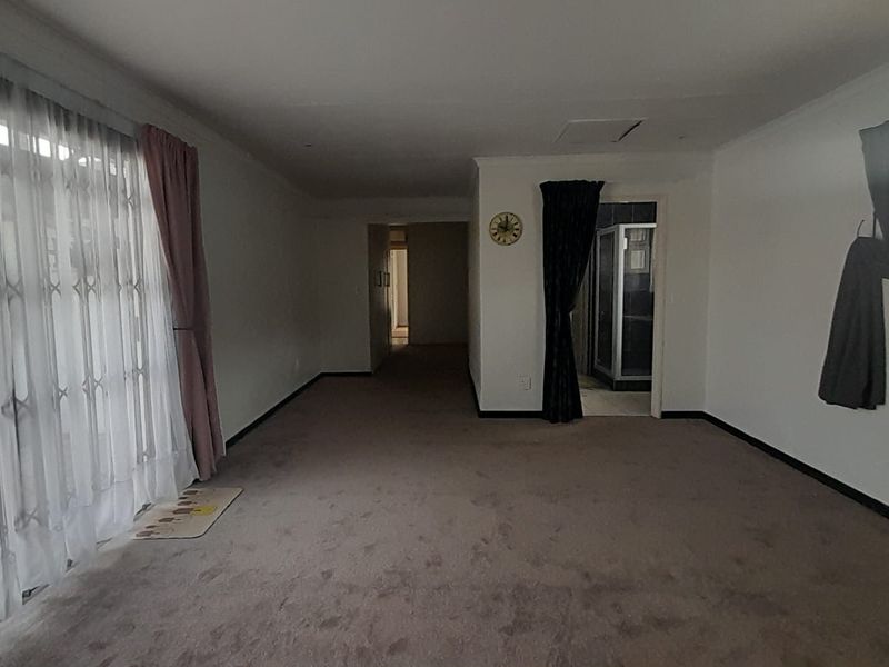 Spacious bedroom featuring neutral carpeting, coving, and direct access to an en-suite bathroom, offering a blank canvas for personalization.