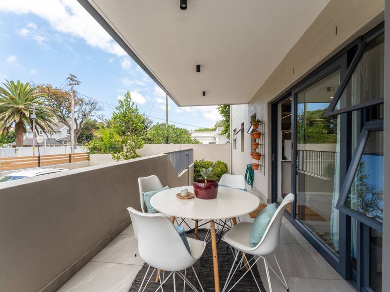A modern, covered balcony featuring tiled flooring, recessed lighting, and large sliding glass doors providing seamless access to the interior living space.