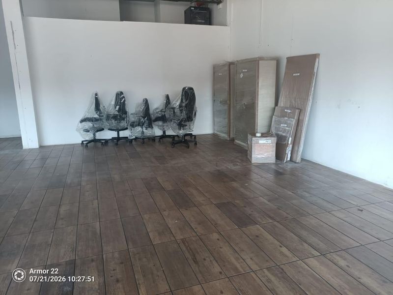 Open plan retail space featuring wood-look tile flooring and neutral white walls, suitable for a variety of commercial business applications.