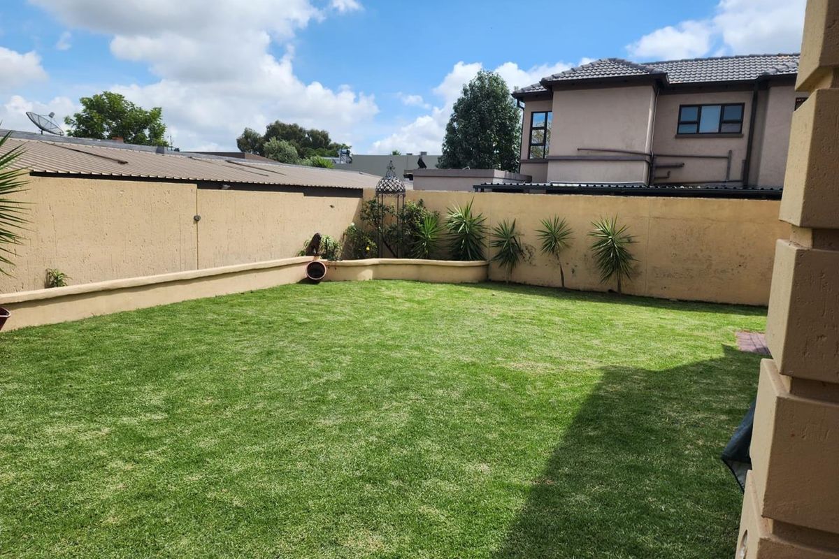 A private, well-maintained rear garden featuring a level lawn, perimeter boundary walls, and established landscaping.