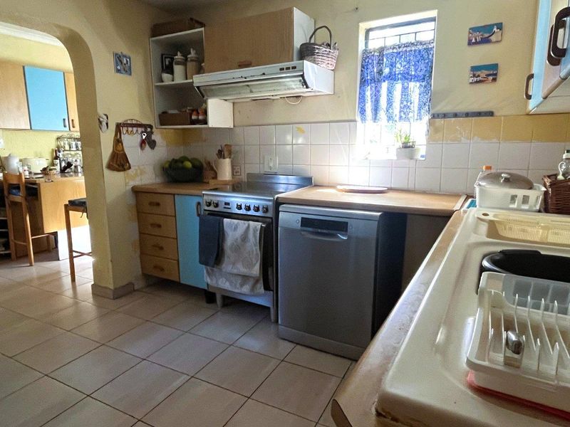 A functional kitchen featuring tiled flooring, a double basin sink, and built-in cabinetry, offering potential for modernization and cosmetic updates.