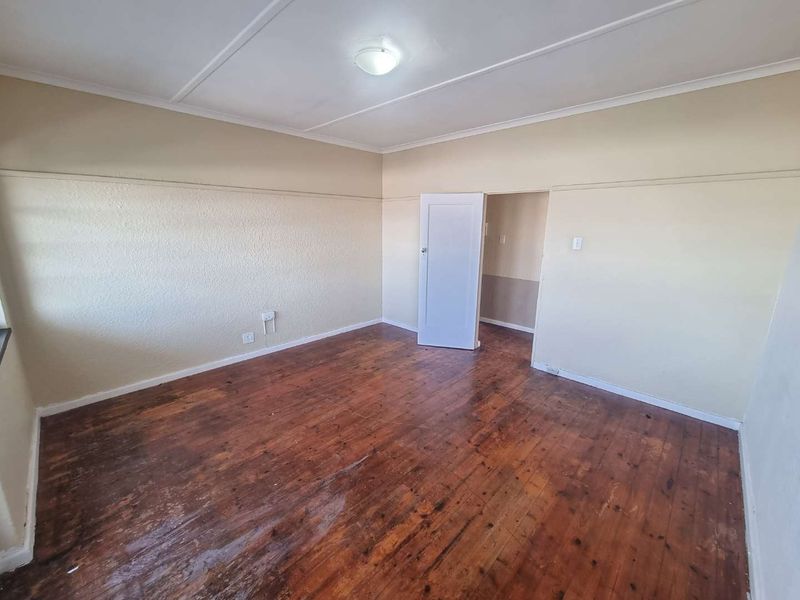 An empty bedroom featuring original hardwood flooring, picture rails, and neutral wall finishes, offering a blank canvas for renovation.
