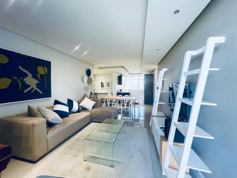 Spacious open-plan living and dining area featuring modern recessed lighting, sleek tiled flooring, and a seamless transition into the contemporary kitchen space.