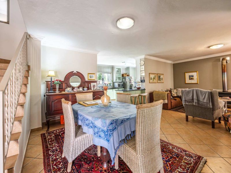 Open plan living and dining area featuring tiled flooring, a wood burning stove, and an adjoining kitchen space with built-in cabinetry.