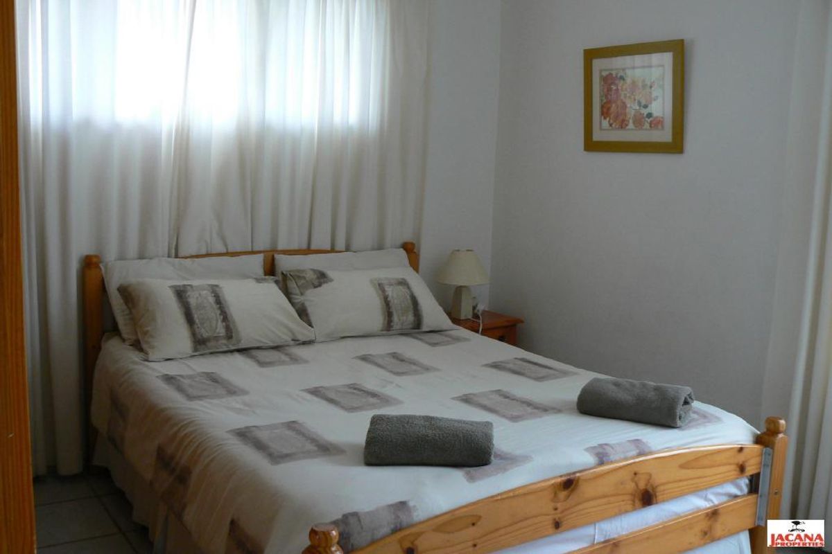 A functional bedroom featuring tiled flooring and floor-to-ceiling curtains, providing a simple and neutral living space.