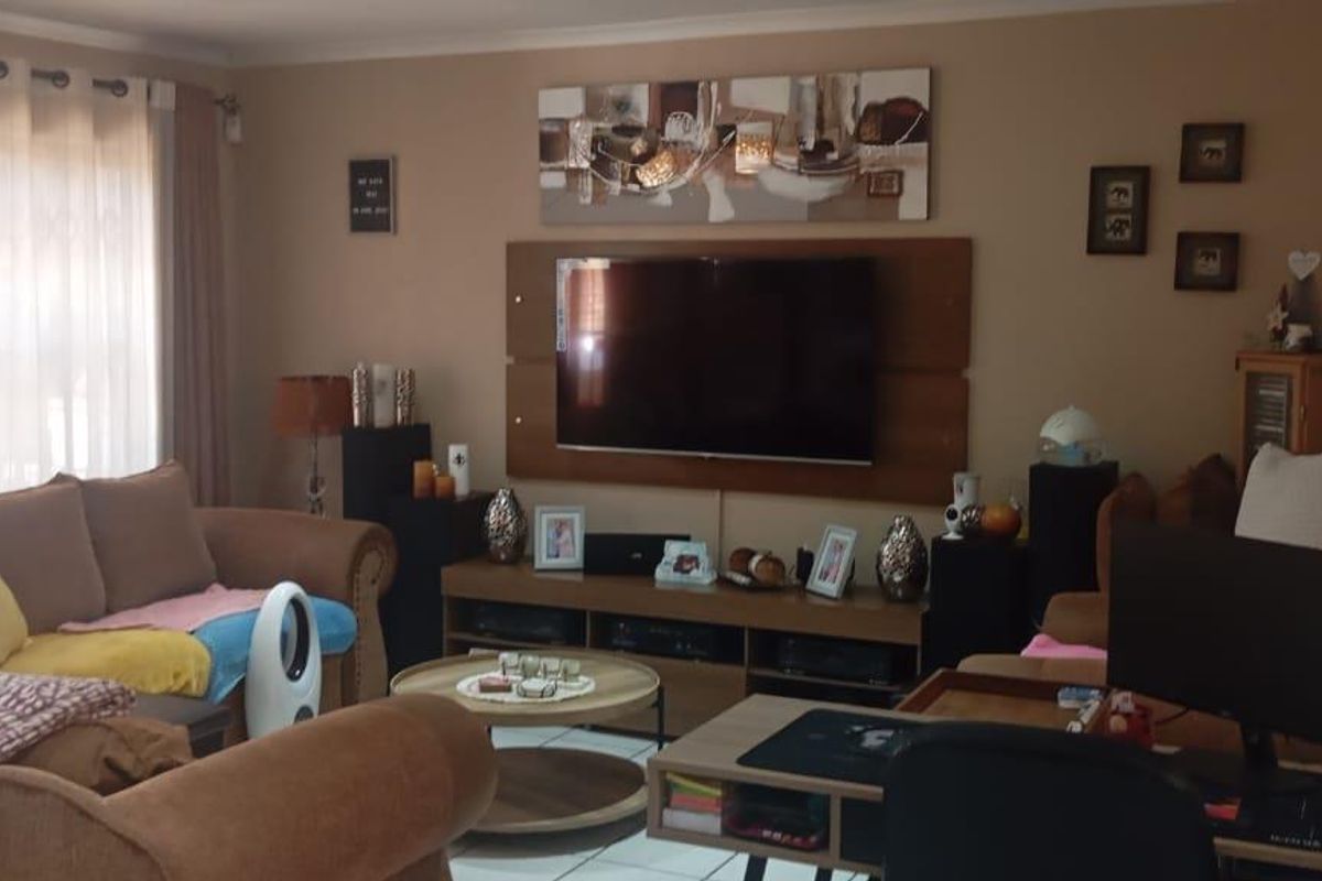 A comfortable living room area featuring tiled flooring and a wall-mounted television unit, creating a functional and inviting space for relaxation.