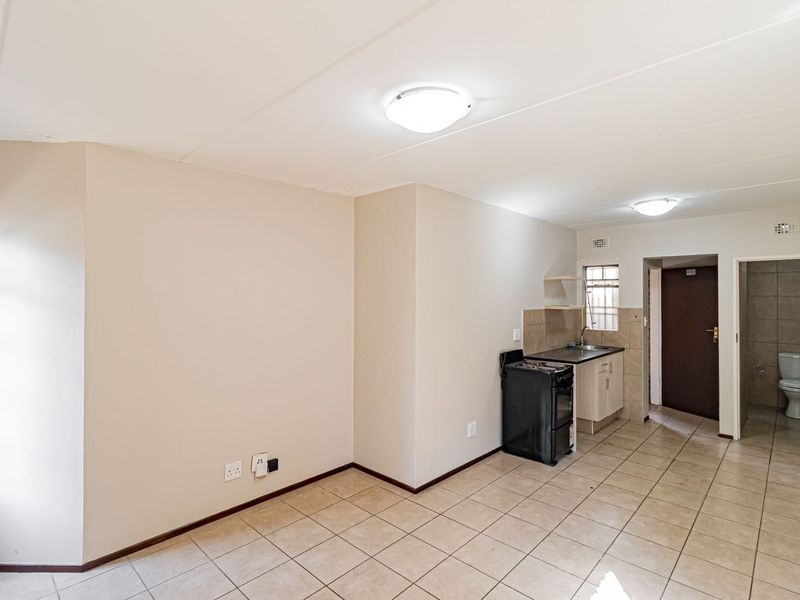 Open-plan living area featuring a compact kitchenette with basic cabinetry and an adjacent bathroom with standard sanitary fixtures.