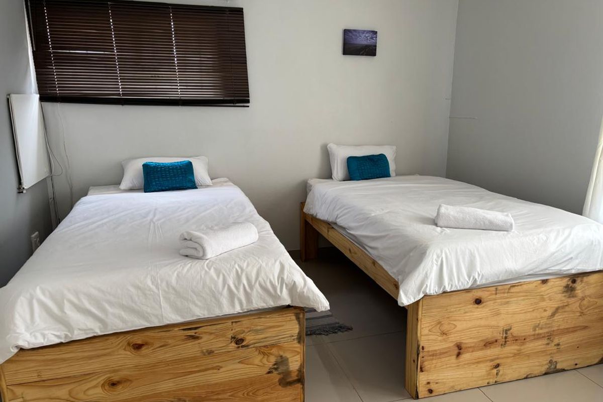 A bedroom featuring tiled flooring and window blinds, currently configured with two single beds.