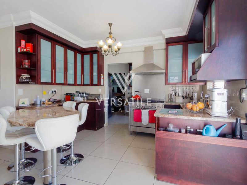 A functional kitchen featuring dark wood cabinetry, granite countertops, a stainless steel extractor fan, and tiled flooring.