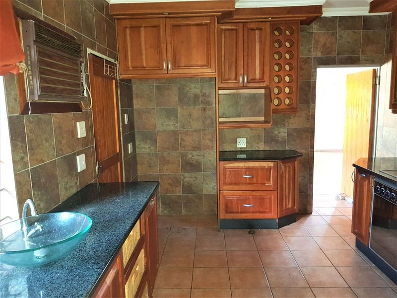 A kitchen featuring wooden cabinetry, granite countertops, and tiled surfaces, offering a functional layout with built-in storage and oven.