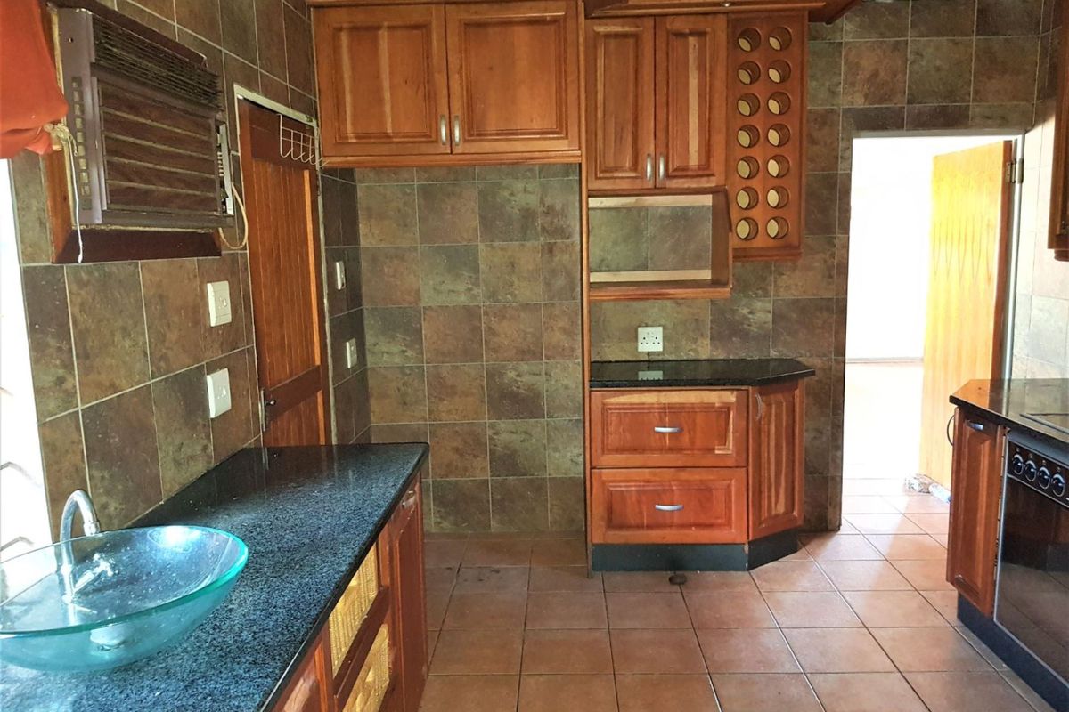 A kitchen featuring wooden cabinetry, granite countertops, and tiled surfaces, offering a functional layout with built-in storage and oven.